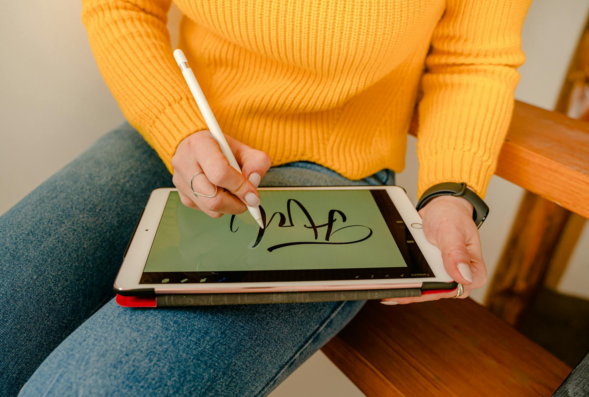 person in yellow sweater holding white tablet