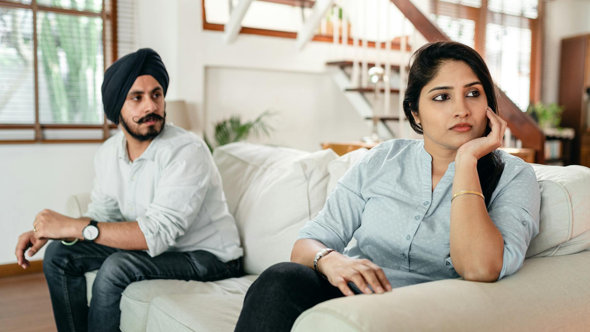 upset young indian couple having argument while sitting on couch